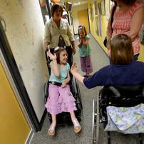 Michigan fan Emily Lickman, 7, of South Lyon, smiles as she looks to high-five friend Kaitlin Barrett-Huff, 11, of Ann Arbor, in the hallway outside of the radio booth. The two were selected to speak on air with their mothers as part of the Mott Takeover at 1050 WTKA on Friday, May 17, 2013. Melanie Maxwell I AnnArbor.com